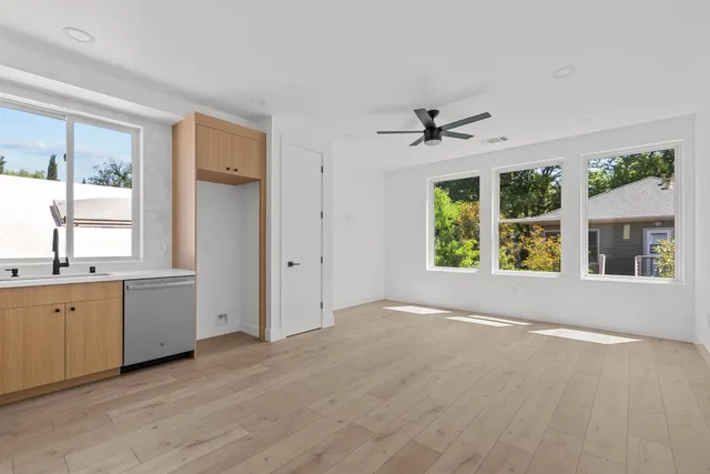 a view of an empty room with a window and a kitchen view