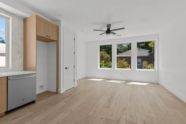 a view of an empty room with a window and wooden floor