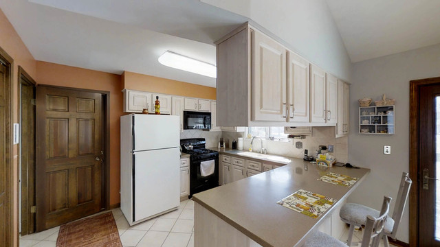 1870 Golfview Drive Bartlett, IL 60103 - Photo 5 of 15 a kitchen with a refrigerator a stove a sink and white cabinets with wooden floor