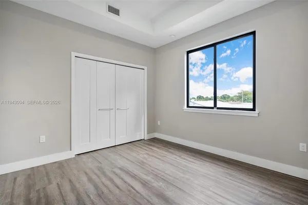 a view of an empty room with wooden floor and a window