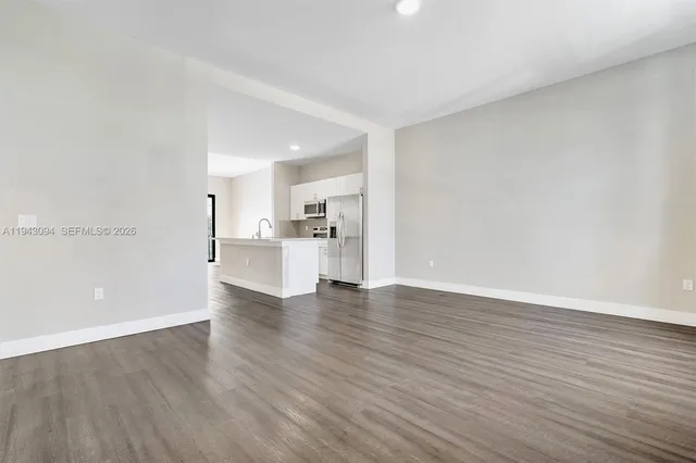 a kitchen with stainless steel appliances granite countertop a refrigerator a stove top oven a sink and dishwasher with wooden floor