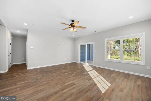 an empty room with windows and chandelier fan