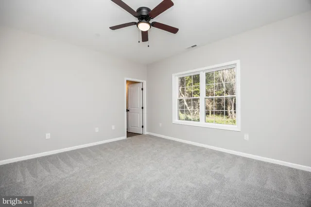 an empty room with closet and a ceiling fan