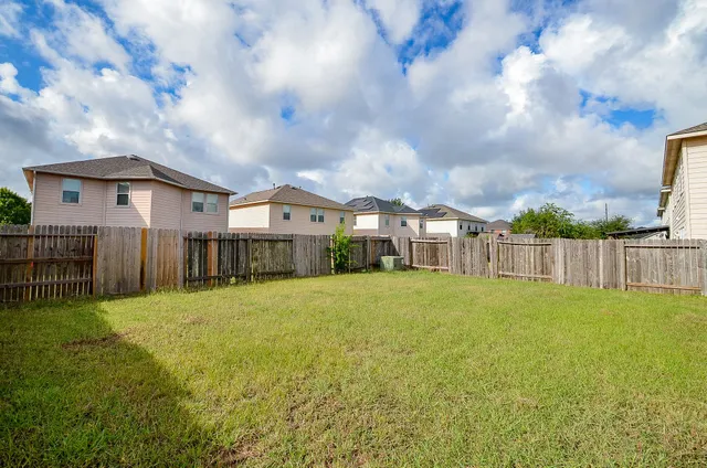 a view of a house next to a big yard with wooden fence