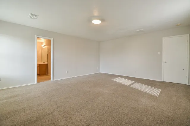 a view of an empty room with wooden floor and windows