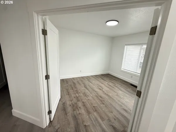 an empty room with wooden floor and windows