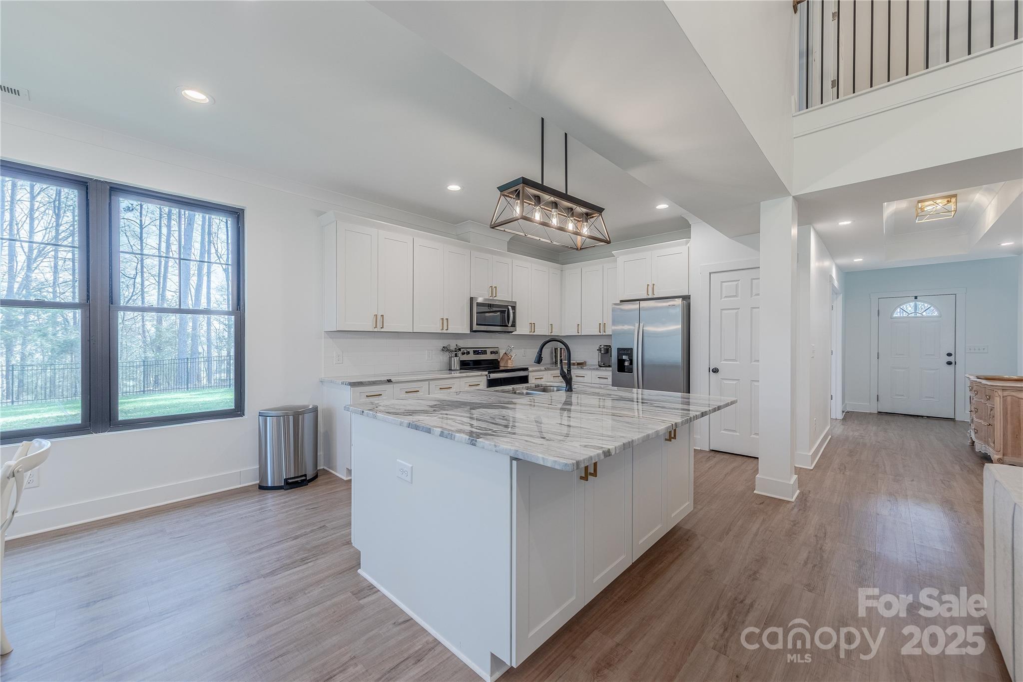 13625 Buster Road Stanfield, NC 28163 - Photo 12 of 43 a large white kitchen with a large window a sink and stainless steel appliances