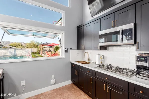 a kitchen with stainless steel appliances kitchen island granite countertop a table chairs sink and cabinets