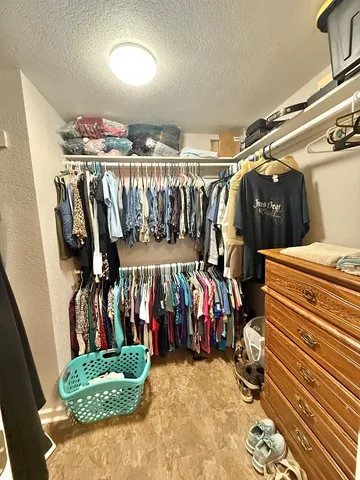 a view of walk in closet with clothes and shoes