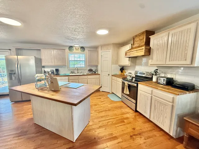 a kitchen with stainless steel appliances granite countertop a kitchen island a stove a sink a refrigerator and cabinets