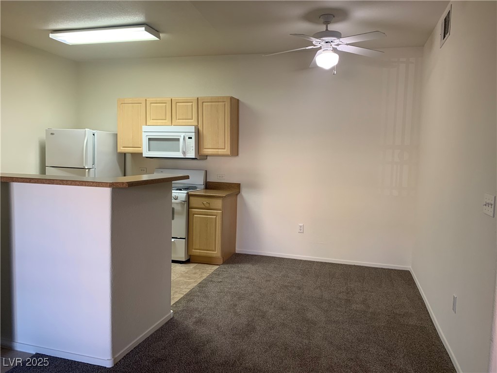 8250 North Grand Canyon Drive, Unit 1158 Las Vegas, NV 89166 - Photo 11 of 40 Kitchen with light brown cabinets, white appliances, light colored carpet, and a ceiling fan