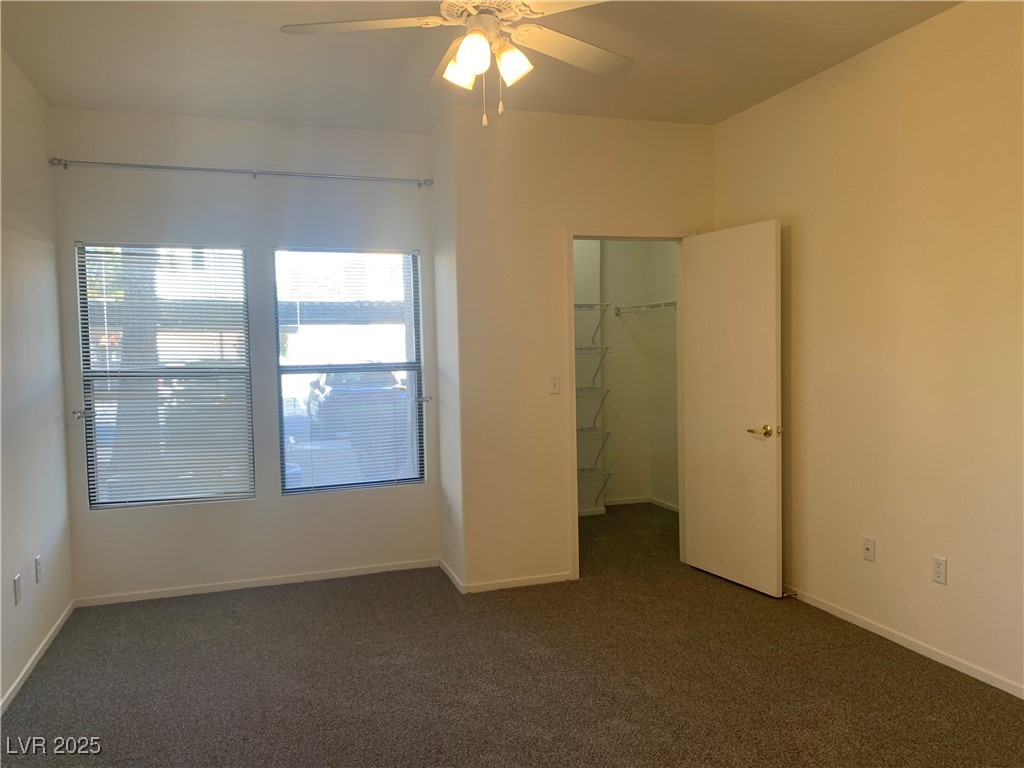 8250 North Grand Canyon Drive, Unit 1158 Las Vegas, NV 89166 - Photo 15 of 40 Unfurnished bedroom with dark colored carpet, a spacious closet, and ceiling fan