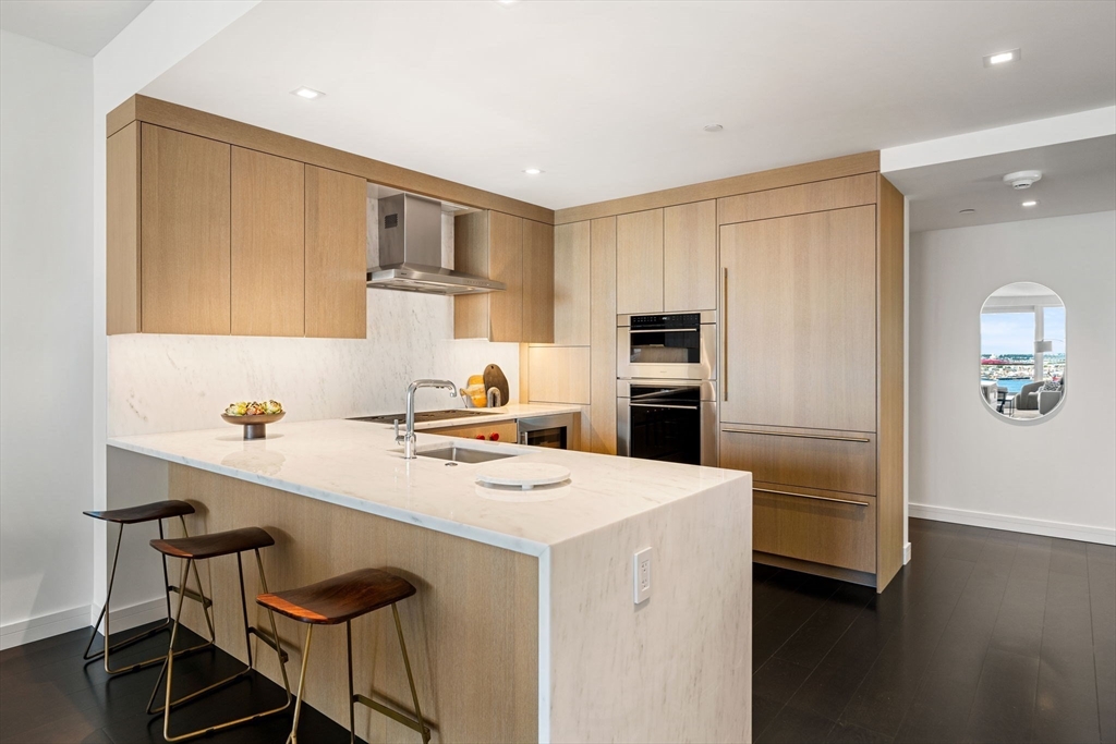 150 Seaport, Unit 9C Boston, MA 02210 - Photo 11 of 39 a kitchen with a sink a stove a refrigerator cabinets and wooden floor