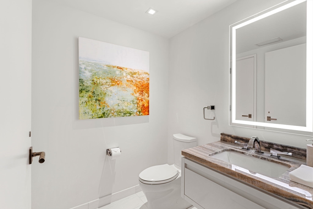 150 Seaport, Unit 9C Boston, MA 02210 - Photo 12 of 39 a bathroom with a granite countertop toilet a sink and mirror