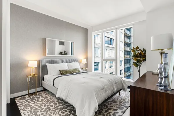 a bedroom with a bed and a table in it with a large window