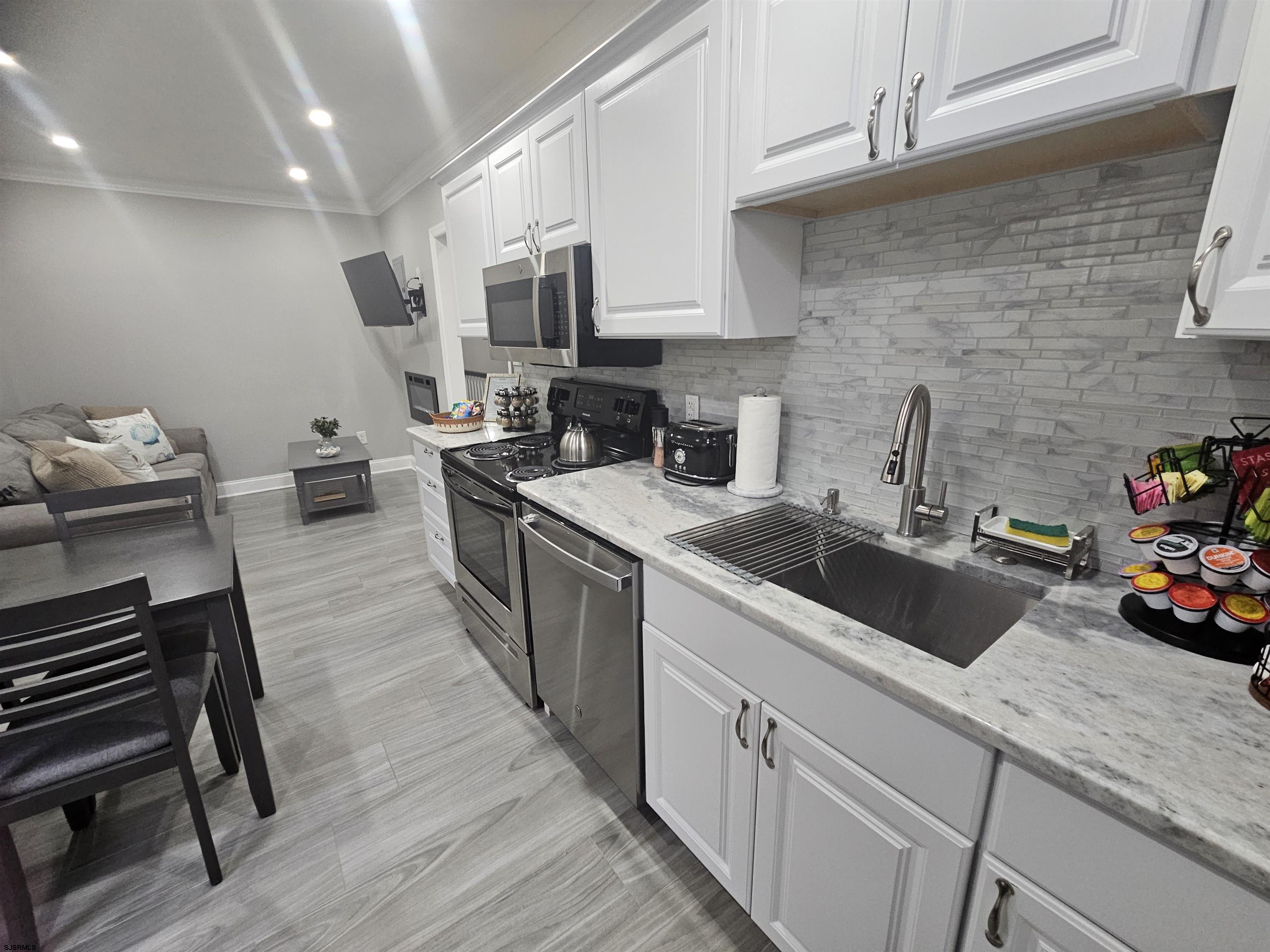 4009 Ventnor, Unit 2 Atlantic City, NJ 08401 - Photo 16 of 32 a kitchen that has a sink and a stove with wooden floors