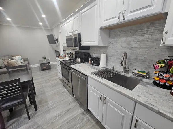 a kitchen that has a sink and a stove with wooden floors