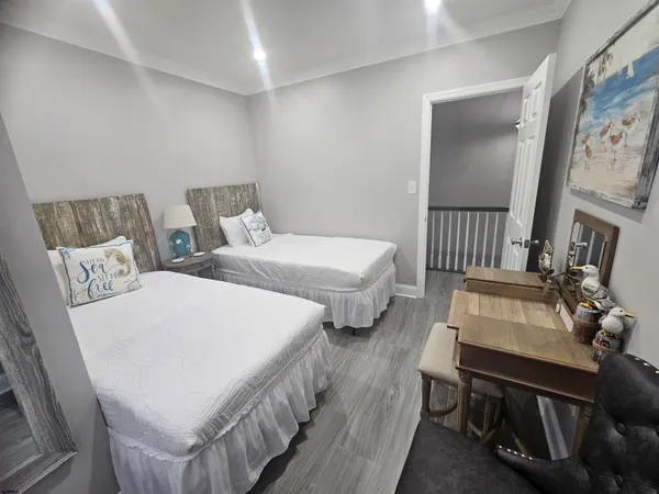 a bedroom with two beds a couch and a dresser with wooden floor