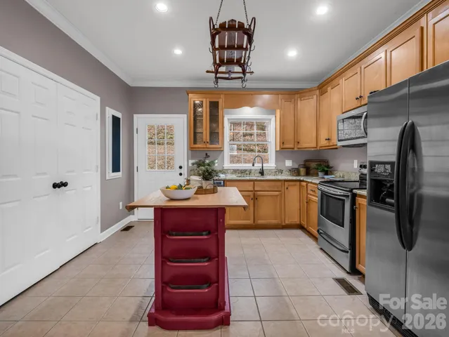 a kitchen with stainless steel appliances granite countertop a stove a sink dishwasher a refrigerator and a dining table with wooden floor