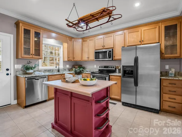 a kitchen with stainless steel appliances granite countertop a sink a stove a refrigerator cabinets and a window
