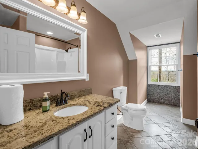 a bathroom with a granite countertop sink mirror vanity and toilet