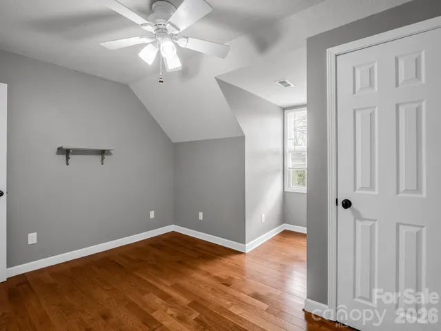 wooden floor in an empty room with a chandelier fan