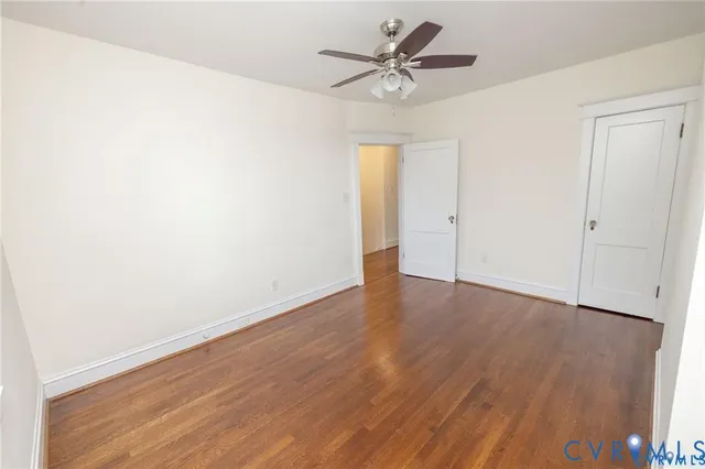 an empty room with wooden floor and ceiling fan