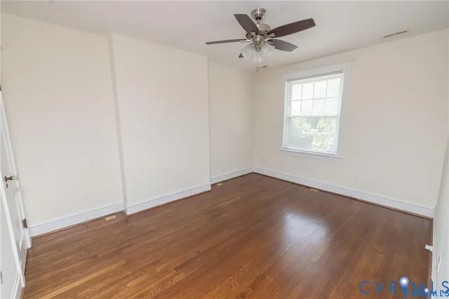 an empty room with wooden floor fan and windows
