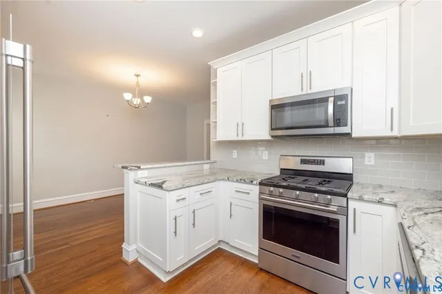 a kitchen with cabinets stainless steel appliances and wooden floor