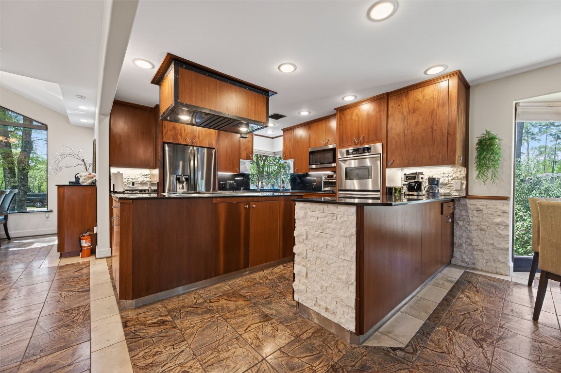 16914 Creeksouth Road Houston, TX 77068 - Photo 12 of 50 a kitchen with kitchen island granite countertop wooden cabinets a counter top space and stainless steel appliances
