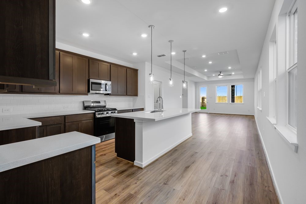 22119 Strathfield Circle Cypress, TX 77433 - Photo 4 of 37 a kitchen with stainless steel appliances kitchen island granite countertop a stove a sink and a microwave