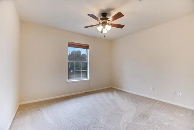 an empty room with a window and a fan