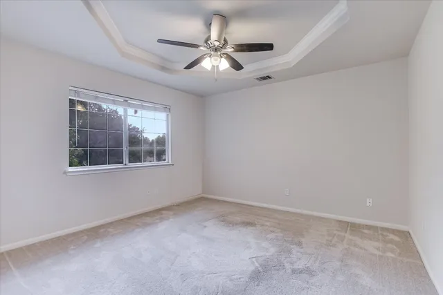 an empty room with windows and fan