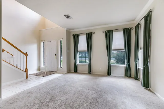 a view of an empty room with window and stairs