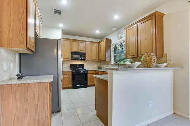 a kitchen with kitchen island granite countertop a sink counter top space cabinets and stainless steel appliances