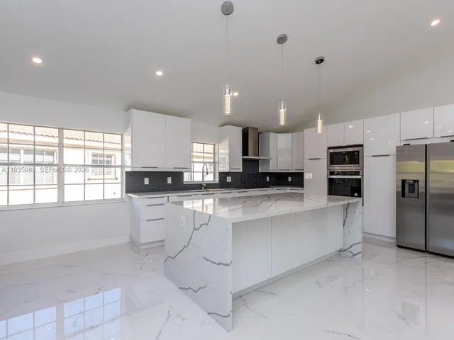 a kitchen with granite countertop white cabinets and window