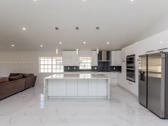 a view of cabinets with stainless steel appliances kitchen island large window and wooden floor