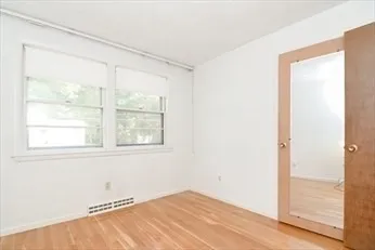 a view of an empty room with wooden floor and a window