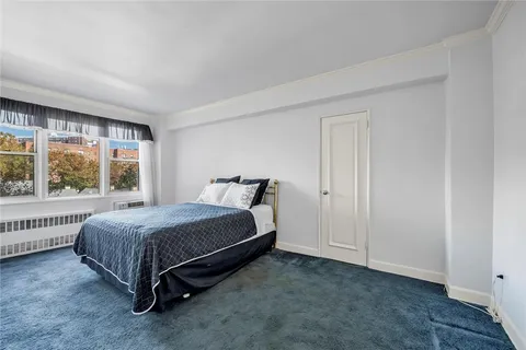 a bed sitting in a spacious bedroom next to a window