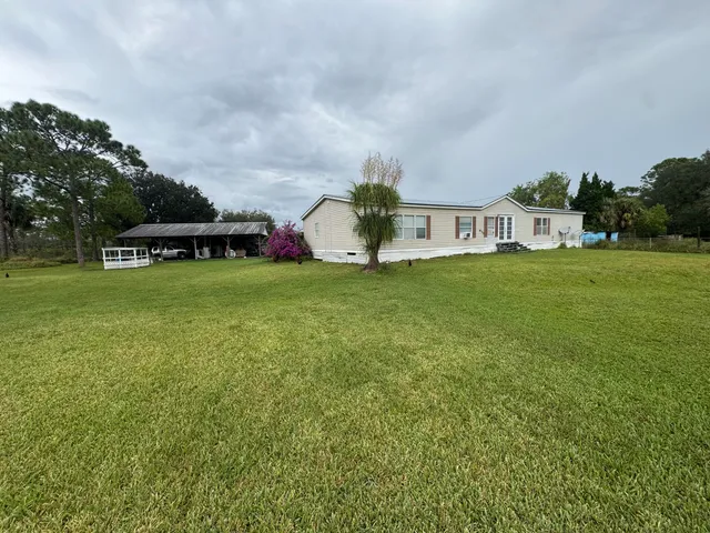 a view of a house with a big yard and large trees