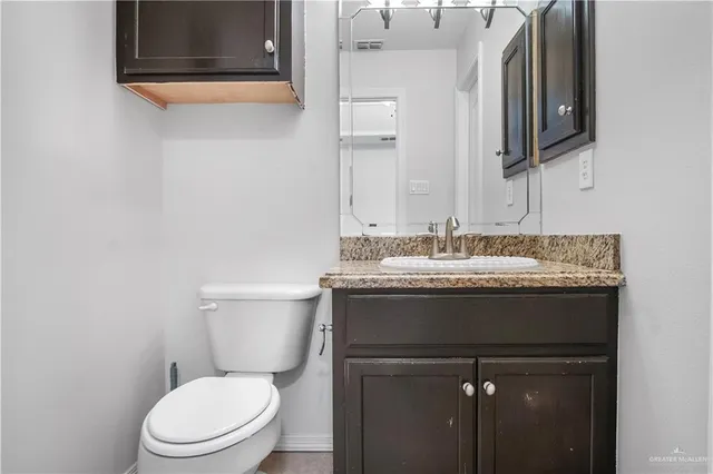 a bathroom with a granite countertop toilet a sink and a mirror