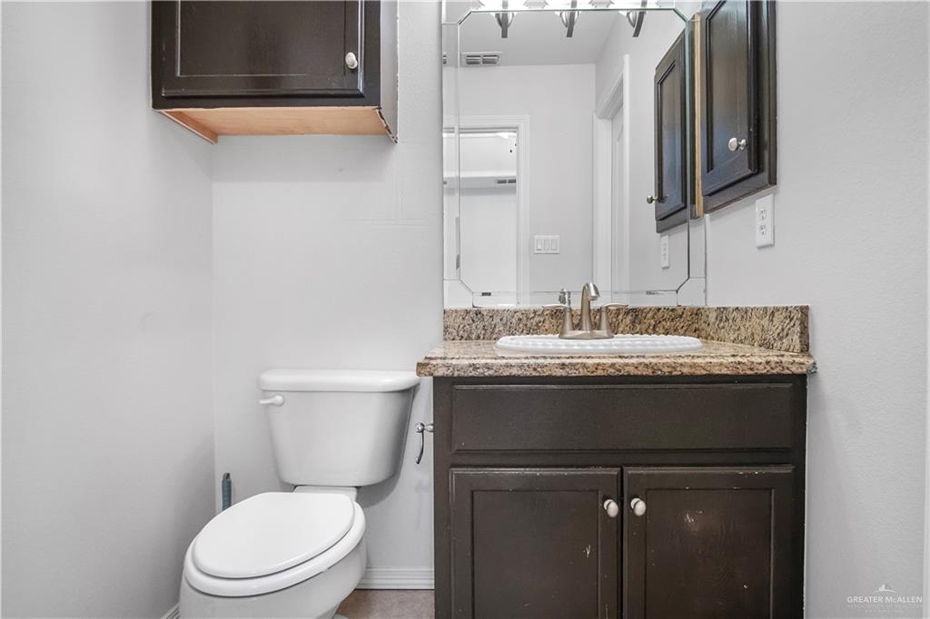 1309 West Fig Avenue, Unit A Pharr, TX 78577 - Photo 13 of 15 a bathroom with a granite countertop toilet a sink and a mirror