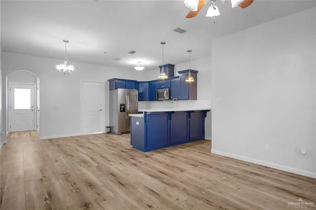 a view of kitchen and empty room with wooden floor