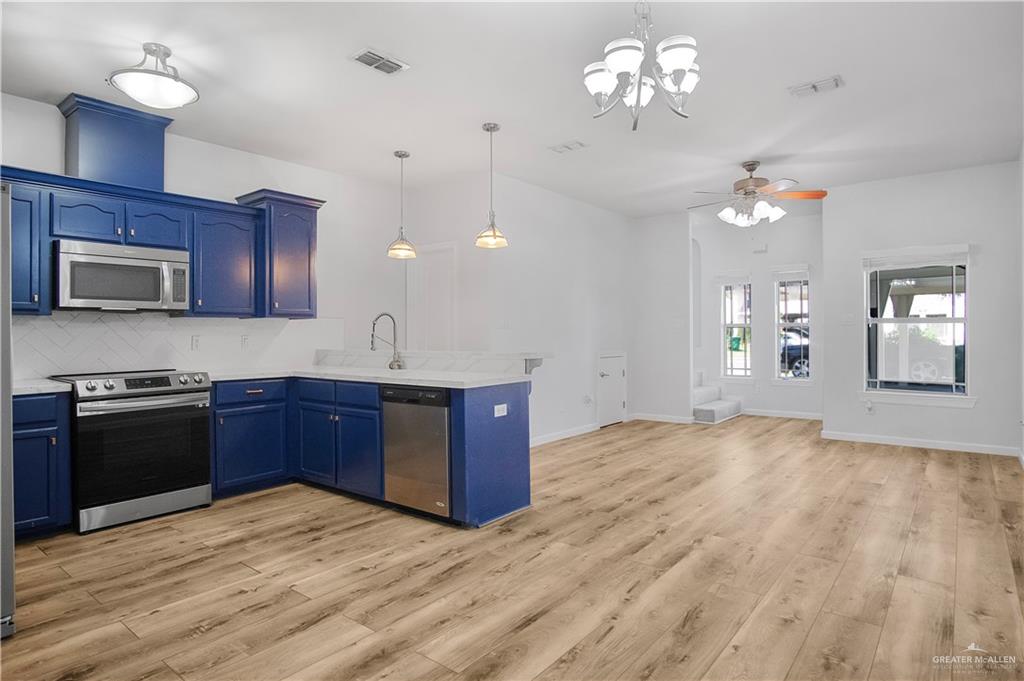 1309 West Fig Avenue, Unit A Pharr, TX 78577 - Photo 5 of 15 a kitchen with kitchen island granite countertop wooden floors granite counter tops and white cabinets