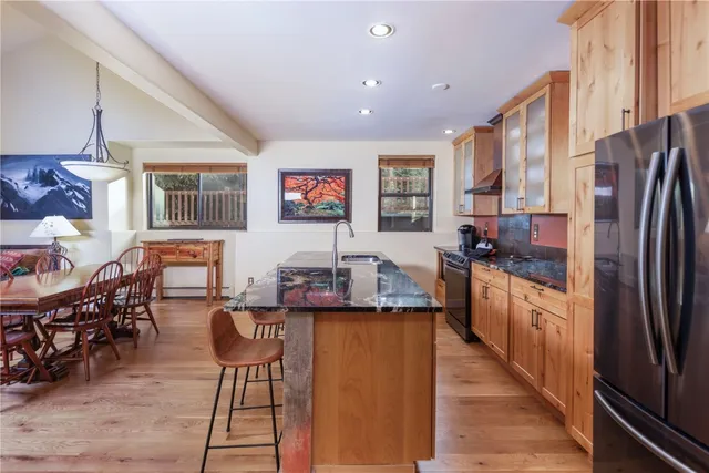 a kitchen with stainless steel appliances kitchen island granite countertop a refrigerator a stove a sink dishwasher with a dining table and chairs