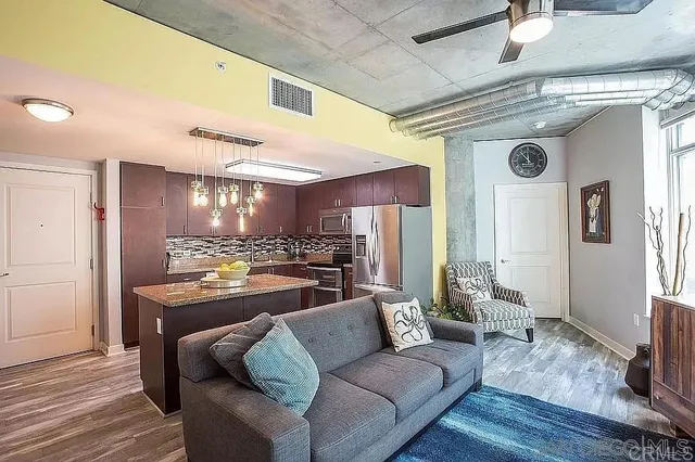 a living room with stainless steel appliances kitchen island granite countertop furniture and a wooden floor
