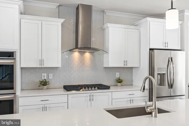 a kitchen with stainless steel appliances kitchen island granite countertop a dining table chairs and white cabinets