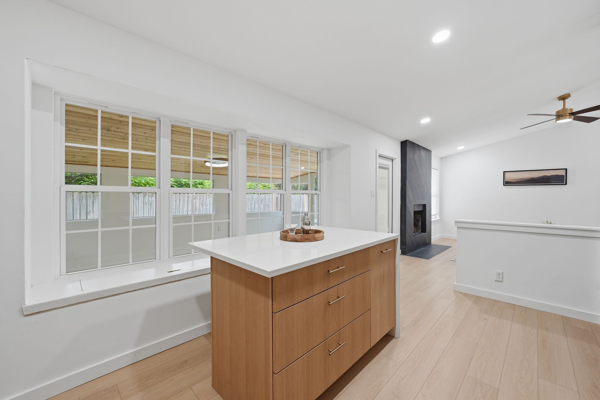6804 Meadow Run Austin, TX 78745 - Photo 11 of 34 This bright interior features light wood flooring, an island with a white countertop and wood cabinetry, and a modern fireplace with a dark stone surround