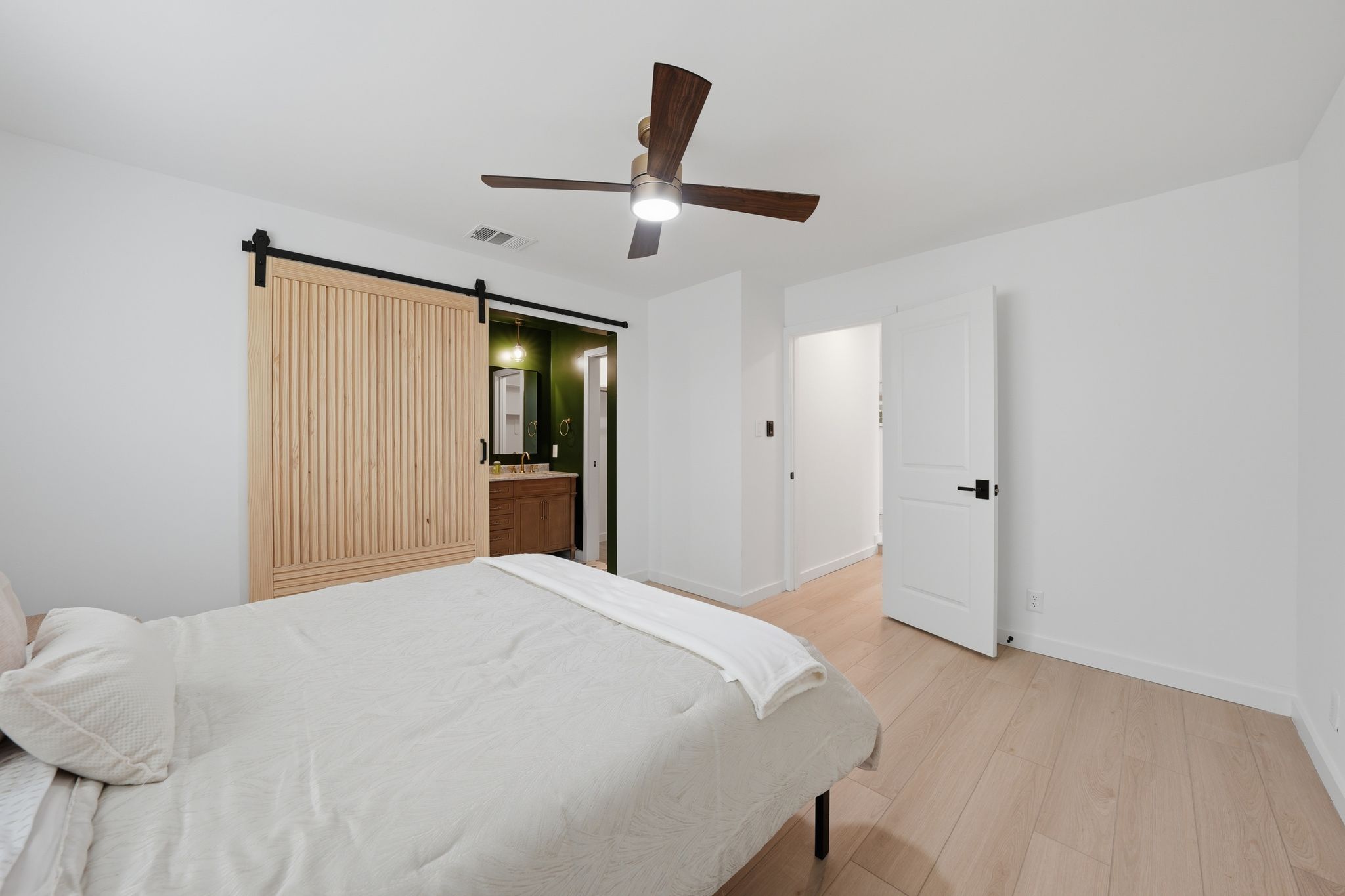 6804 Meadow Run Austin, TX 78745 - Photo 14 of 34 Living space featuring light-toned wood flooring, a ceiling fan, and a light wood barn door with a black track
