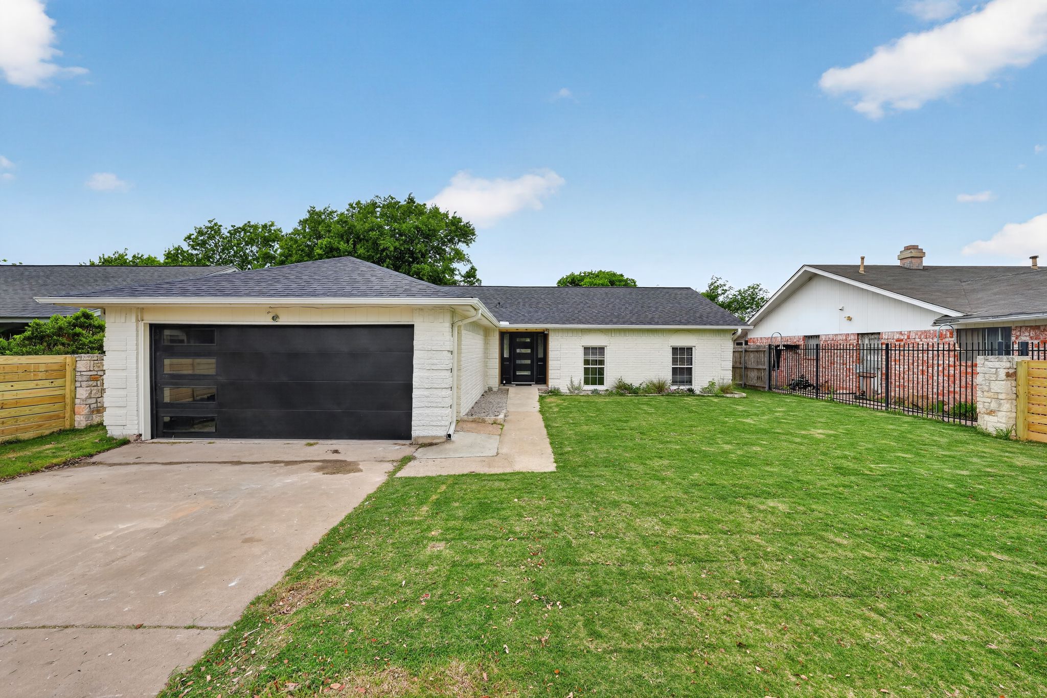 6804 Meadow Run Austin, TX 78745 - Photo 2 of 34 The property features a well-maintained front yard with a lawn, a paved driveway, and a modern garage door with frosted glass panels